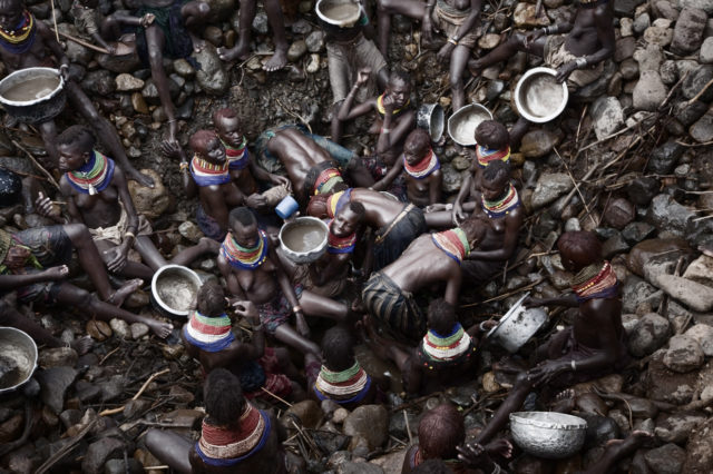 © Stefano de Luigi Turkana women retrieve water for people and cattle from a twenty-meter deep, homemade borehole, in Kaitede, Rift Valley Province, Kenya on Oct. 3 2009. Kenya hasn’t seen a drop of rain for several years and is now facing a devastating drought. Livestock and crops are dying and people are getting weaker every day. The lack of resources in Kenya and in neighbouring countries is sparking intertribal conflicts as communities fight for limited grazing land and water. The spread of weapons is turning those conflicts bloody. 09/10/2009 © Stefano de Luigi